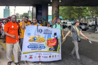 Visually impaired persons and volunteers participate in an awareness walk in Lagos to commemorate International White Cane Safety Day.