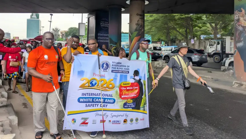 Visually impaired persons and volunteers participate in an awareness walk in Lagos to commemorate International White Cane Safety Day.